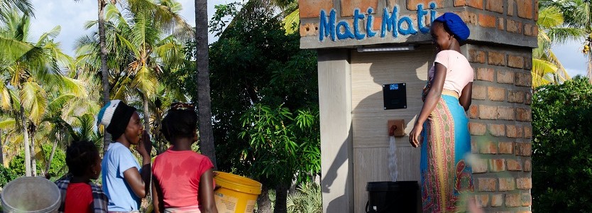 Frauen vor einer Zapfsäule des Mati Mati (Wasser Wasser) Projekts. 