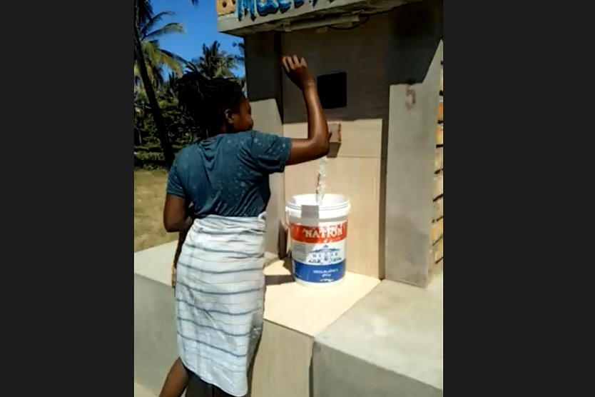 Frau zapft Wasser in Mozambik.